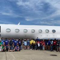 Group photo of campers outside an airplane